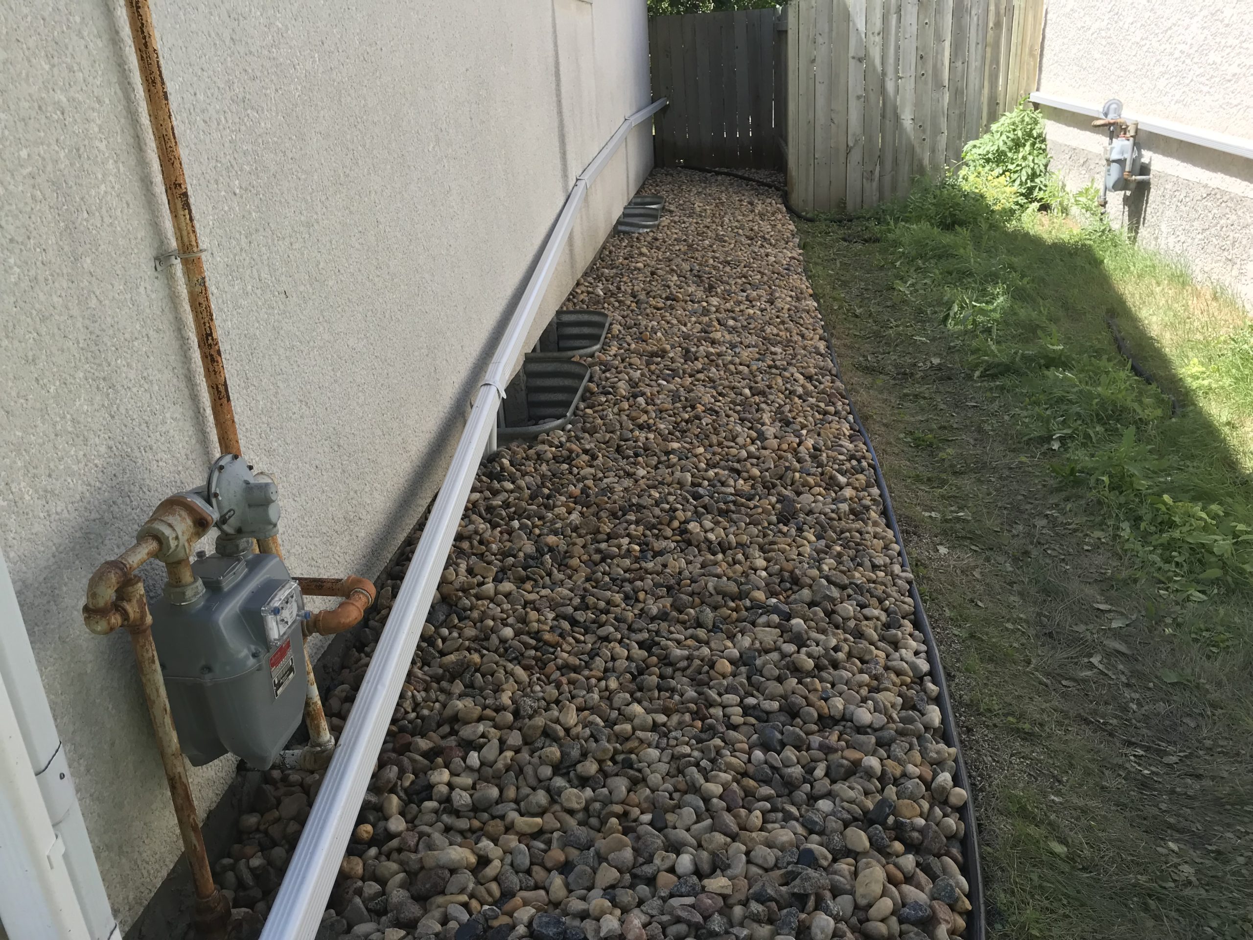 Front-yard garden bed refresh with decorative rock and fresh plantings by D&J Yardworks